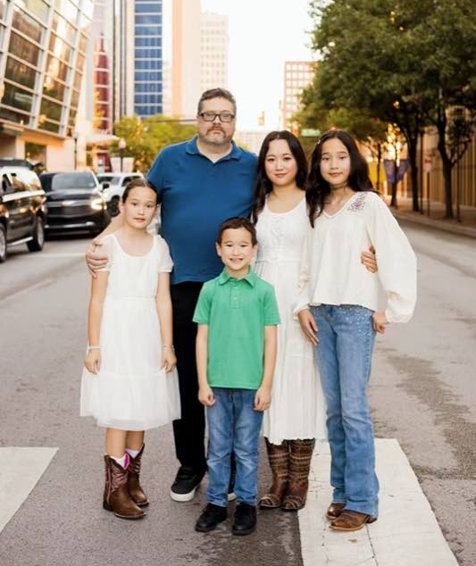 Brian Crosson with his family on a street in downtown Fort Worth, the city skyline behind them.